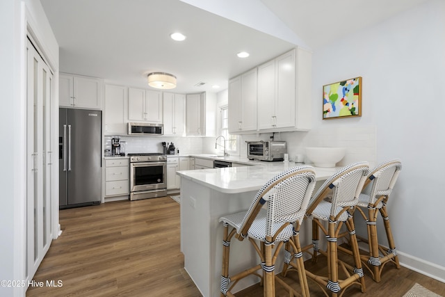 212 Florida Ave, Carolina Beach, NC 28428 - kitchen with stainless steel appliances, a sink, a peninsula, decorative backsplash, and light countertops