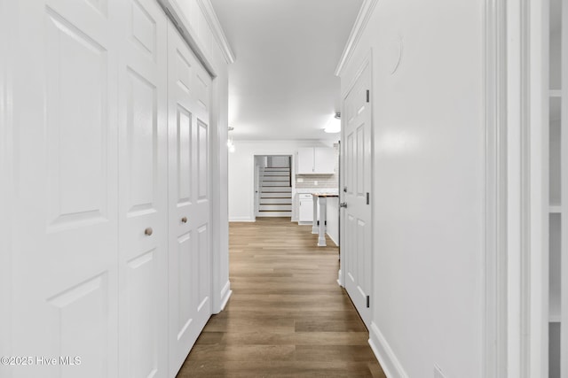 hallway with crown molding, baseboards, and wood finished floors