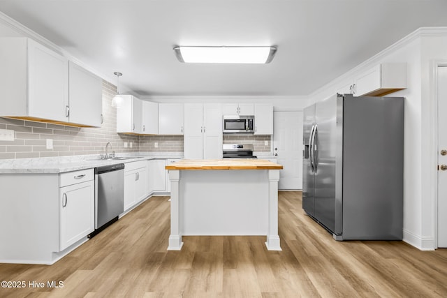 kitchen with a kitchen island, hanging light fixtures, stainless steel appliances, white cabinetry, and wooden counters