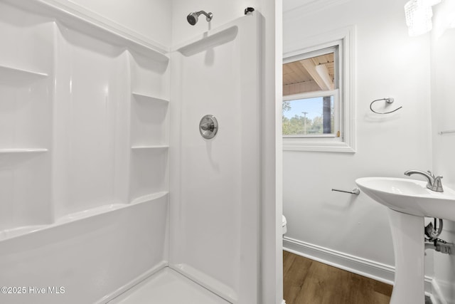 bathroom featuring wood finished floors, a shower stall, toilet, and baseboards