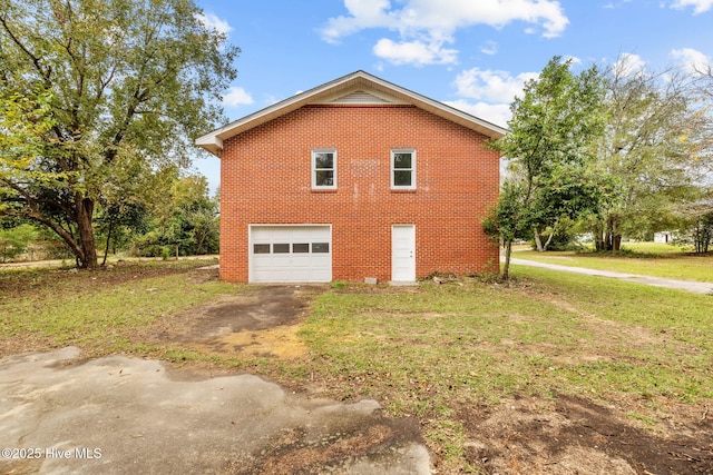 view of property exterior featuring a garage, brick siding, a yard, and driveway