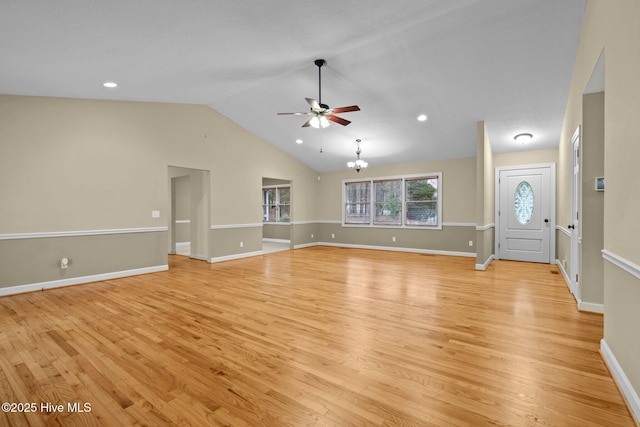 unfurnished living room with vaulted ceiling, ceiling fan with notable chandelier, baseboards, and light wood-style floors