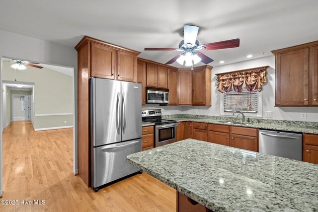 kitchen featuring appliances with stainless steel finishes, brown cabinetry, and a sink