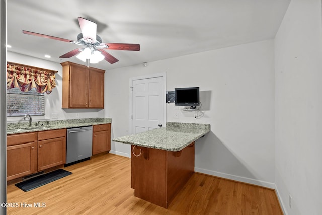 kitchen featuring light wood-type flooring, brown cabinets, a sink, and stainless steel dishwasher