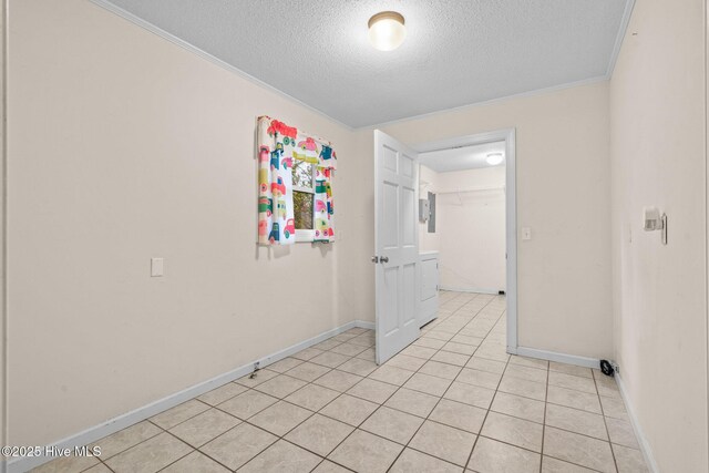 empty room with light tile patterned floors, crown molding, baseboards, and a textured ceiling