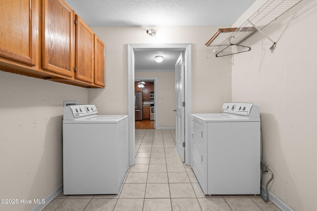 washroom with cabinet space, a textured ceiling, washer and dryer, and light tile patterned flooring