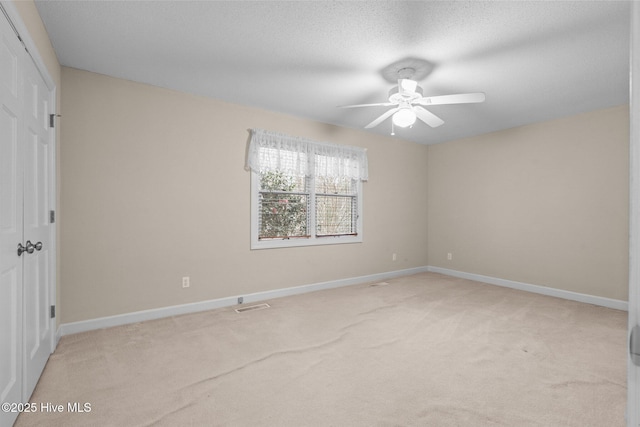 unfurnished bedroom with light carpet, a textured ceiling, a ceiling fan, and baseboards