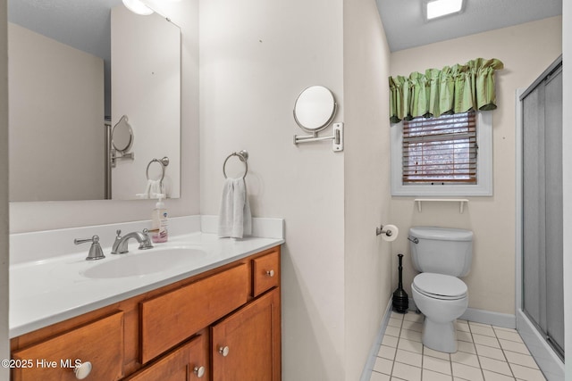 full bath featuring toilet, a stall shower, vanity, baseboards, and tile patterned floors