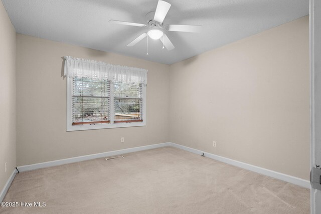 carpeted empty room with ceiling fan, visible vents, and baseboards