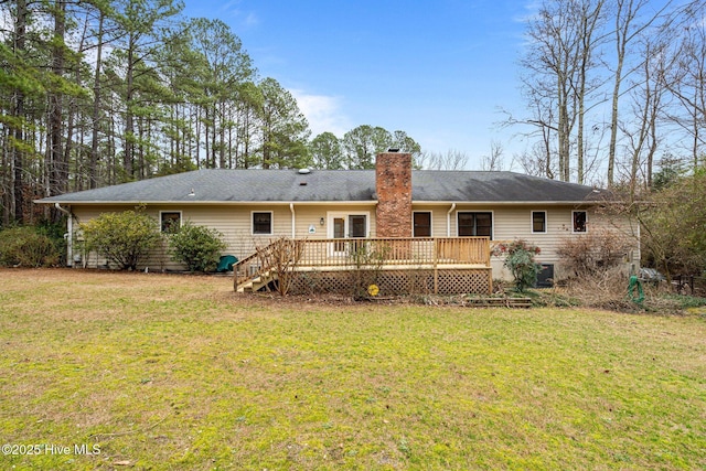 rear view of property with a chimney, a lawn, and a wooden deck