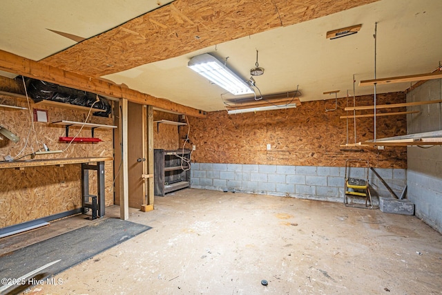 basement featuring a garage, a workshop area, and concrete block wall