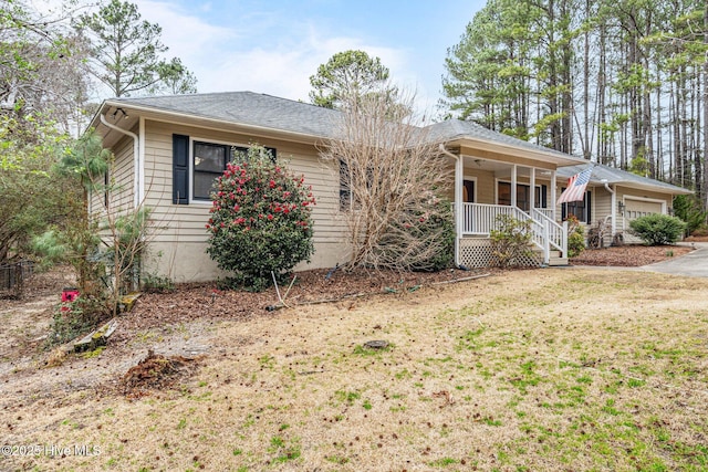 ranch-style house featuring covered porch, a shingled roof, a front lawn, and a garage