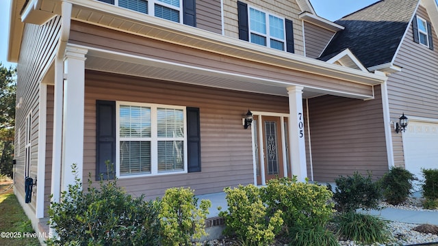 entrance to property with covered porch and roof with shingles