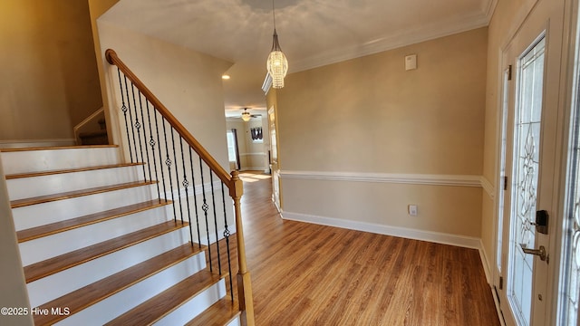 foyer with stairway, crown molding, baseboards, and wood finished floors