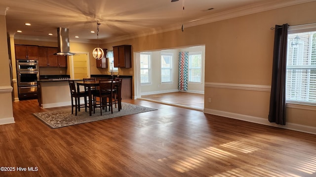 dining area featuring crown molding, baseboards, and wood finished floors