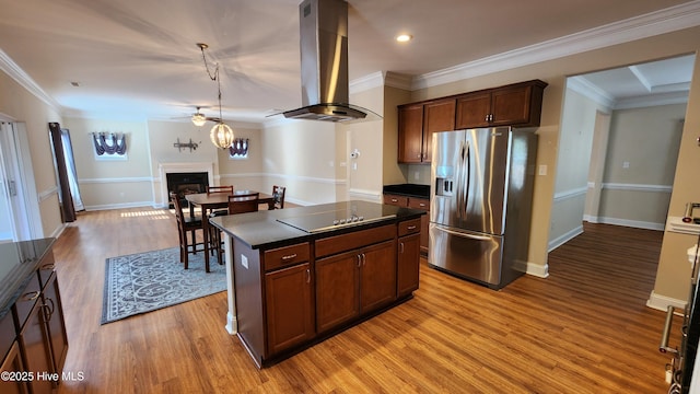 kitchen with a center island, a fireplace, island exhaust hood, stainless steel refrigerator with ice dispenser, and dark countertops