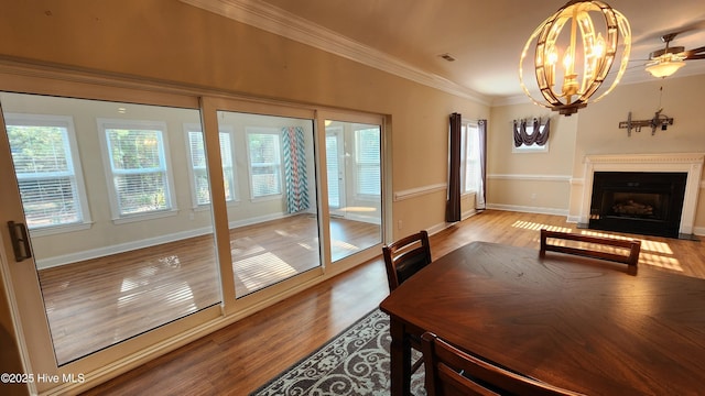 dining space featuring wood finished floors, a fireplace with flush hearth, visible vents, baseboards, and ornamental molding