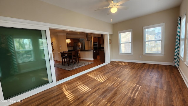 empty room with ceiling fan, dark wood-type flooring, and baseboards