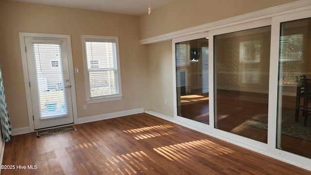 doorway with dark wood-type flooring and baseboards