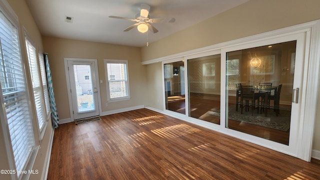 unfurnished sunroom featuring a healthy amount of sunlight, ceiling fan, and visible vents