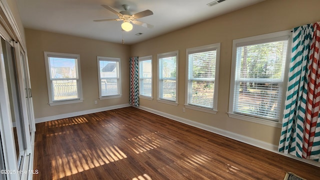 empty room with baseboards, dark wood-type flooring, and a wealth of natural light