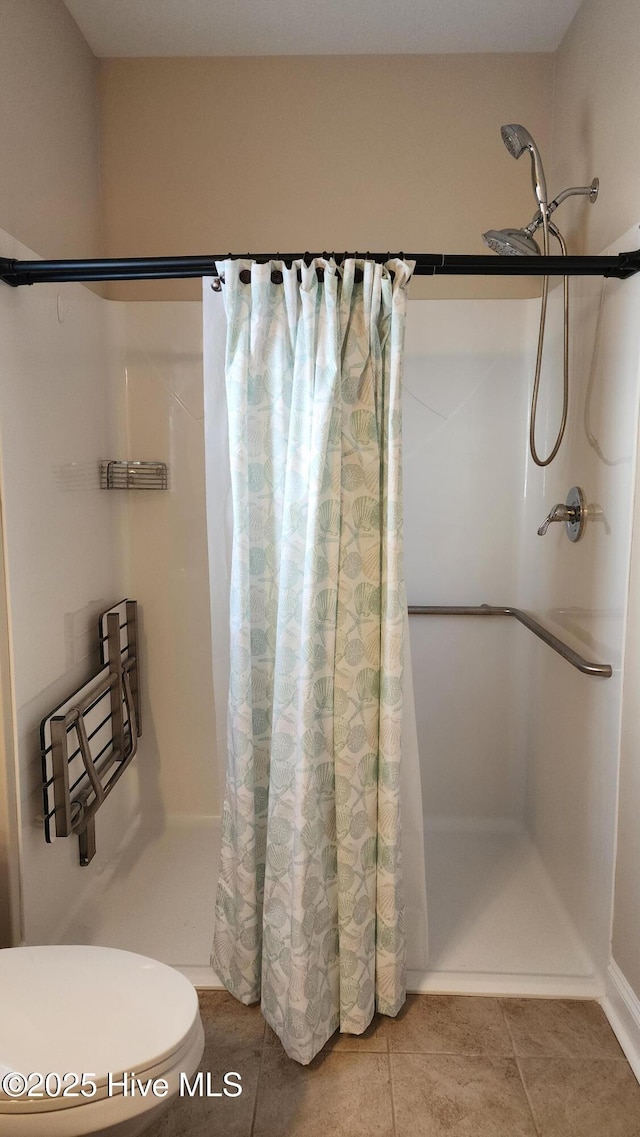 bathroom with a stall shower, tile patterned flooring, and toilet