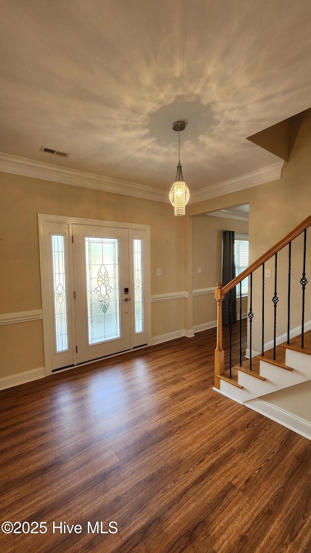 foyer featuring plenty of natural light, stairs, visible vents, and dark wood finished floors