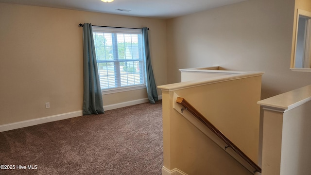 interior space featuring visible vents, baseboards, carpet flooring, and an upstairs landing