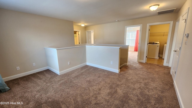 unfurnished room with carpet floors, washer / dryer, baseboards, and visible vents