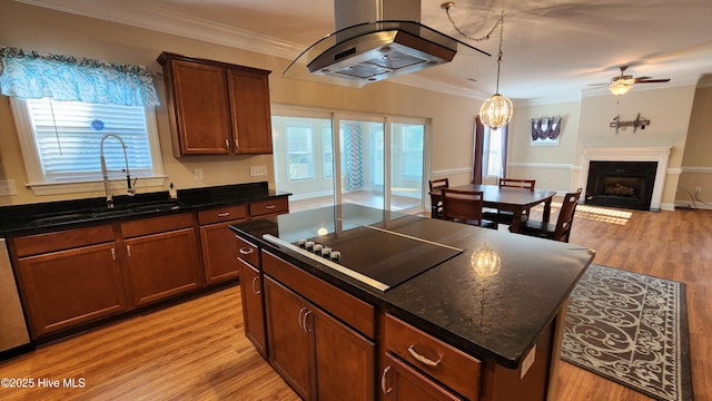 kitchen with black electric cooktop, a fireplace, a kitchen island, a sink, and light wood-style floors