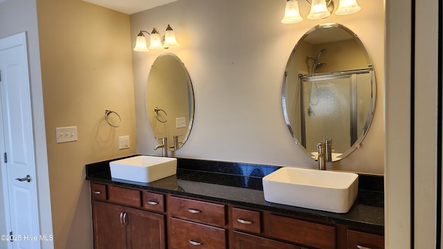 bathroom with double vanity, a sink, and a shower with door