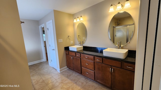 bathroom with double vanity, an enclosed shower, a sink, baseboards, and tile patterned floors