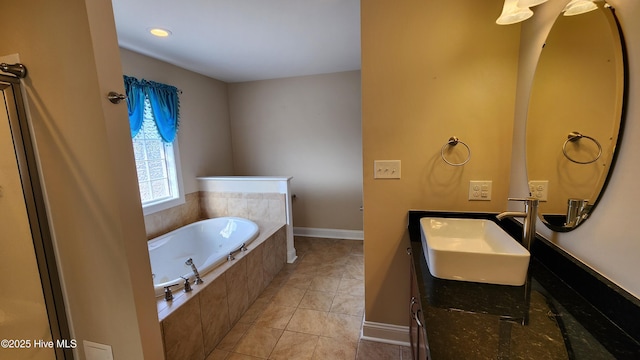 bathroom with a garden tub, vanity, baseboards, and tile patterned floors