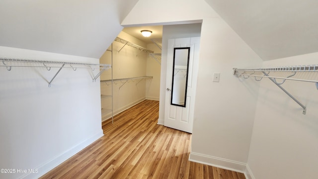 walk in closet with vaulted ceiling and wood finished floors