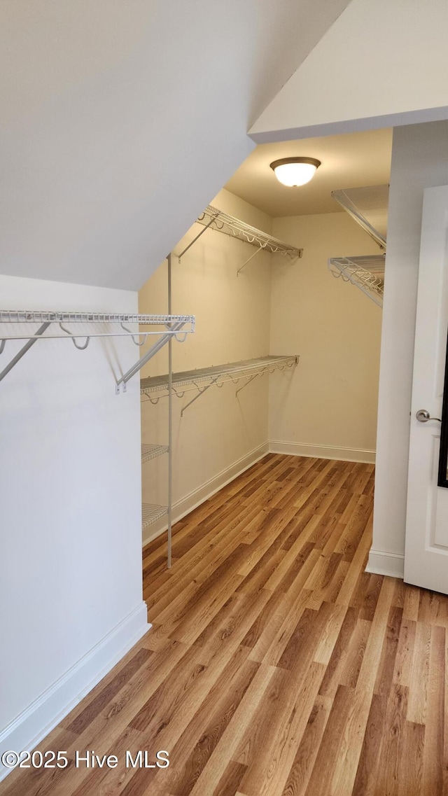 spacious closet with lofted ceiling and wood finished floors