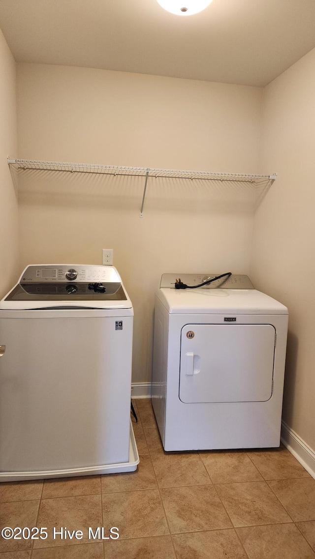 washroom featuring laundry area, light tile patterned floors, baseboards, and separate washer and dryer