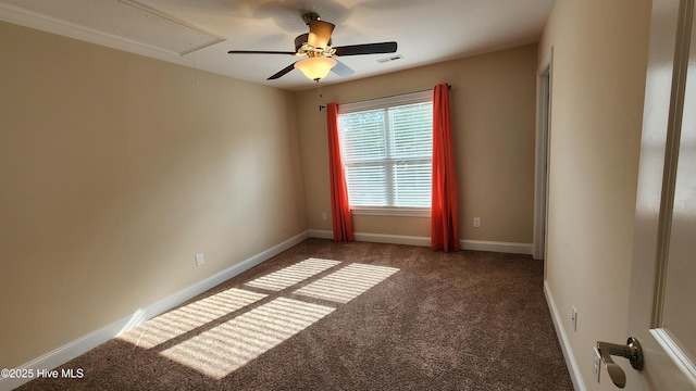 unfurnished room with visible vents, dark colored carpet, attic access, and baseboards