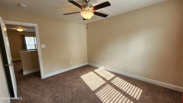 empty room featuring dark colored carpet and baseboards