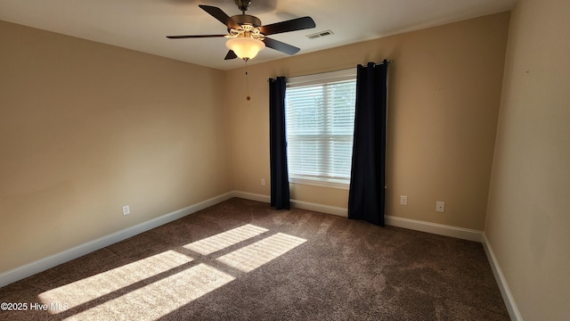 spare room featuring a ceiling fan, dark colored carpet, visible vents, and baseboards