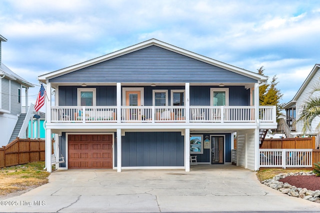 coastal inspired home featuring concrete driveway, stairway, an attached garage, a porch, and board and batten siding