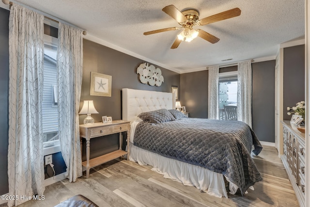 bedroom with a textured ceiling, light wood-type flooring, and a ceiling fan