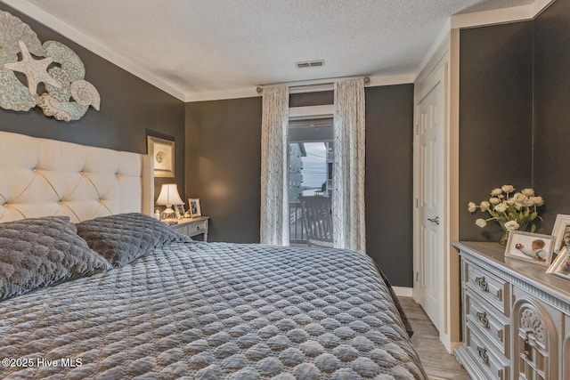 bedroom with visible vents, a textured ceiling, and wood finished floors