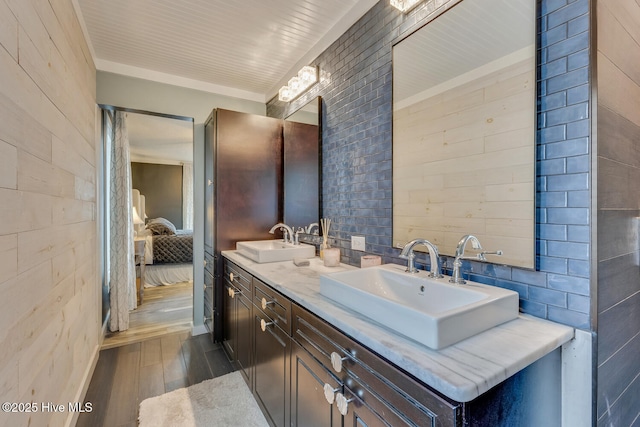 ensuite bathroom featuring double vanity, wood finished floors, a sink, and connected bathroom