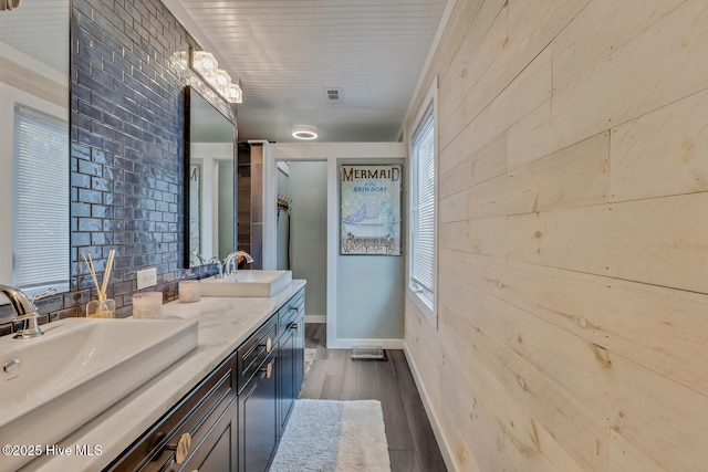 full bathroom with wood finished floors, visible vents, a sink, and double vanity