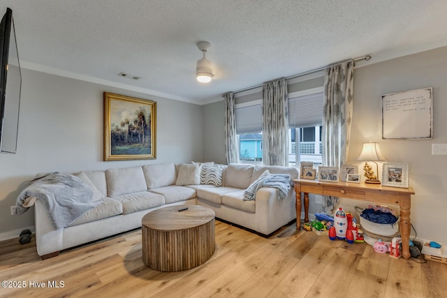 living room featuring light wood-style floors, a textured ceiling, visible vents, and crown molding