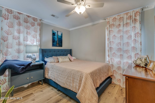 bedroom with a ceiling fan, visible vents, crown molding, and light wood-style flooring