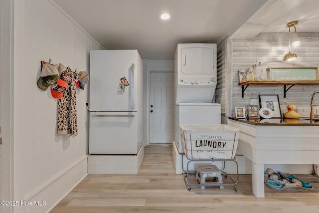 kitchen featuring light wood-style flooring, white cabinets, freestanding refrigerator, dark countertops, and pendant lighting