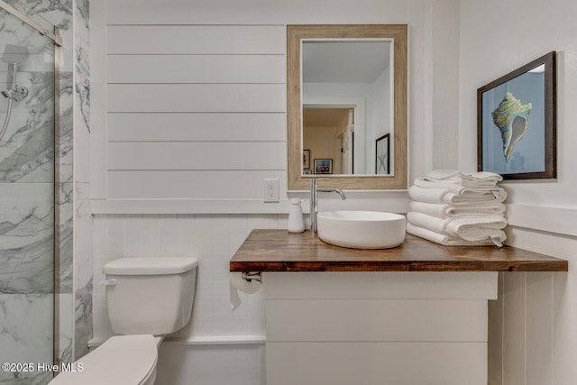 full bath featuring vanity, a marble finish shower, and toilet