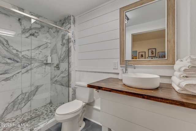 full bath featuring a marble finish shower, wood walls, vanity, and toilet