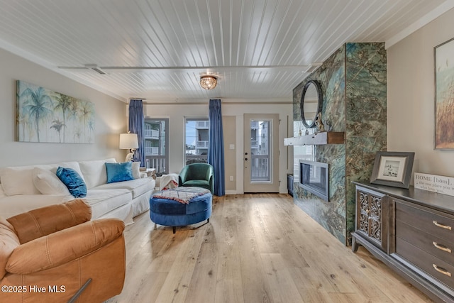 living area with light wood-type flooring, wooden ceiling, and a fireplace